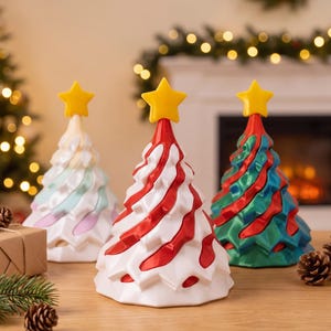 May include: Three conical Christmas tree decorations with a star topper. One is white with red swirls, one is white with pastel blue and pink accents, and one is green with red swirls. Each tree has a textured, layered design and a yellow star.