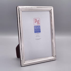 Op de afbeelding: Zilveren fotolijst met een afgeschuinde rand en een witte passe-partout. De lijst heeft een label met de tekst "Pg Miani Venezia".
