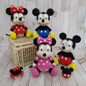 May include: A group of handmade crochet Mickey and Minnie Mouse dolls. The dolls have black ears, white faces, and wear their iconic outfits, including red and pink dresses with white polka dots, and yellow shoes. A small Minnie Mouse head is also included.