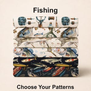 May include: A stack of six fabric swatches featuring fishing-themed patterns. The top four have a cream background with illustrations of fish, lures, and nets. The bottom two have a dark navy background with colorful fish and fishing gear motifs.