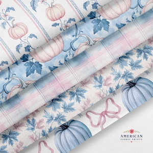 May include: A collection of fabric swatches featuring a pattern of light pink pumpkins, blue leaves, and pink bows on a white background with vertical stripes. The fabric has a visible woven texture and includes the text AMERICAN FABRIC PRINTS.
