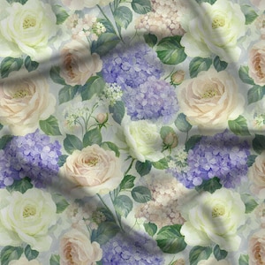 May include: A fabric featuring a repeating floral pattern of cream-colored roses and clusters of purple hydrangeas set against a light background. The design includes green leaves and small white blossoms, creating a dense, layered botanical print.