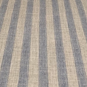 May include: Close-up of a striped fabric with a beige background and blue stripes. The stripes have a diamond pattern.