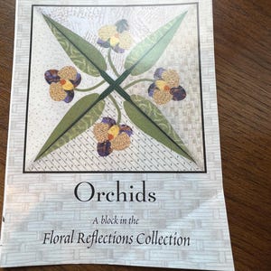 May include: A printed pattern for a quilt block featuring an orchid design. The cover reads "Quilt Nouveau Designs by Binky" and "Orchids, A block in the Floral Reflections Collection." The design includes green leaves and yellow and purple flowers.