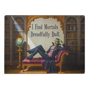 Peut inclure: Planche à découper rectangulaire avec une illustration de vampire. Le vampire à la peau verte est allongé sur une chaise longue. Le texte "I Find Mortals Dreadfully Dull" est affiché au-dessus du vampire.