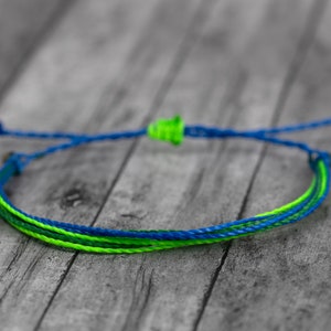 May include: A blue and green braided friendship bracelet with a knot closure.
