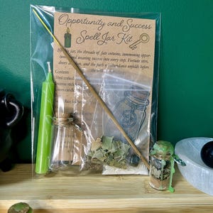 May include: A clear bag containing an "Opportunity and Success Spell Jar Kit." The kit includes a green candle, incense stick, small corked bottles, and dried herbs. The label has text and illustrations.