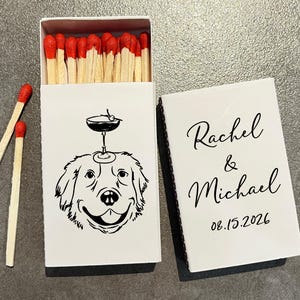 May include: White matchbox with a black illustration of a dog with a cocktail glass on its head. The text "Rachel & Michael 08.15.2026" is on the lid. The match heads are red.