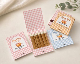 May include: Three matchbooks with pink, orange, and blue gingham patterns. Each features a pumpkin illustration, a bow, and the text Thank You for celebrating with me! Kinsley's 1st Birthday 10.25.2026. One matchbook is open, revealing wooden matches.
