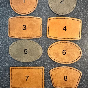 Peut inclure: Présentation de huit patchs en cuir de différentes formes et couleurs. L'ensemble comprend deux cercles, trois rectangles, deux ovales et une forme personnalisée. Chaque patch est bordé de coutures et numéroté de 1 à 8.