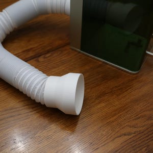 May include: A white plastic ventilation hose with a round, white plastic connector. The hose is flexible and has a ribbed texture.