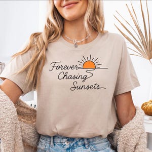 May include: A beige t-shirt with a graphic of a sunset and the text "Forever Chasing Sunsets".