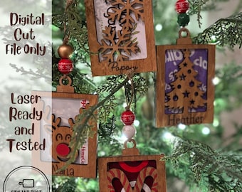 May include: Four rectangular wooden gift card holder ornaments featuring laser-cut designs of a snowflake, a Christmas tree, a reindeer, and candy canes. Each ornament includes colorful beads and personalized names engraved at the bottom.