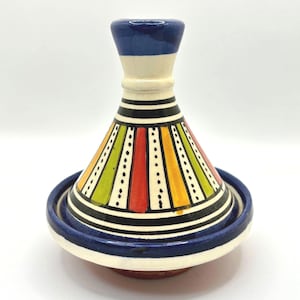 May include: A small, colorful ceramic tagine with a blue, white, green, yellow, and red striped design. The tagine has a domed lid and a round base.