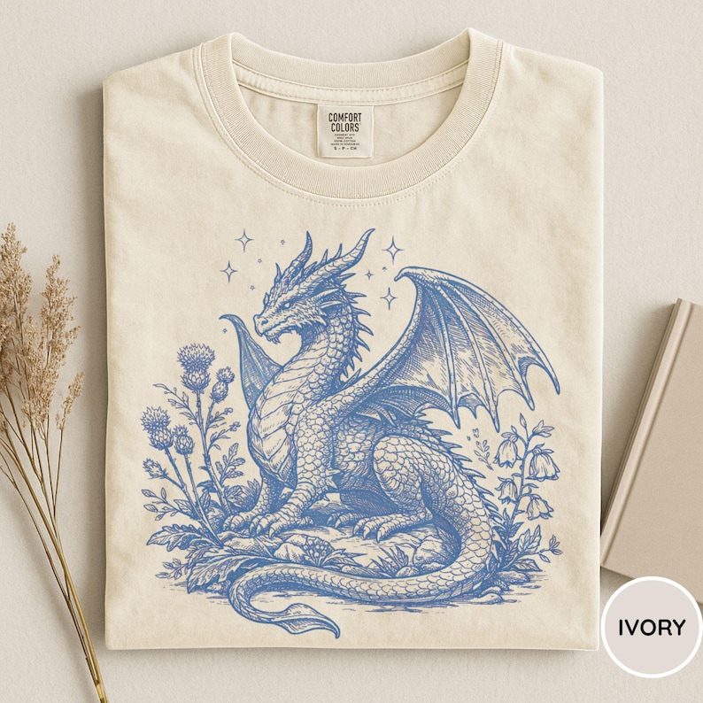 Peut inclure: T-shirt ivoire avec un dessin de dragon bleu d&eacute;taill&eacute;. Le dragon est entour&eacute; de fleurs et d'&eacute;toiles. Le t-shirt porte une &eacute;tiquette Comfort Colors.