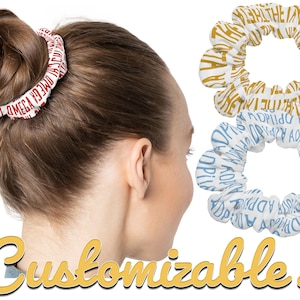 May include: A woman with brown hair wearing a red and white scrunchie with text. Two additional scrunchies are displayed, one gold and white, and one blue and white, each with text. The word "Customizable!" is written in a yellow cursive font.