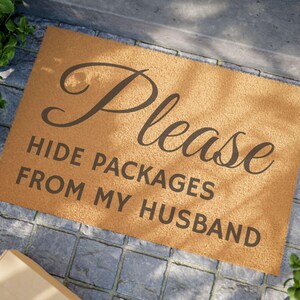 May include: A brown coir doormat with the text "Please hide packages from my husband" in black lettering.