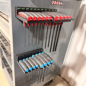 May include: A grey tool cart displaying two sets of Allen keys. The top row features red and black handled keys, sizes from 5/64" to 3/8". The bottom row has blue and black handles, sizes from 2.5 to 10 mm.