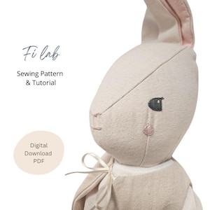 May include: A soft, beige bunny plush toy with pink accents on the ears and cheeks. The bunny has embroidered facial features and is wearing a light-colored vest. Text on the image reads "Fi lab Sewing Pattern & Tutorial" and "Digital Download PDF."