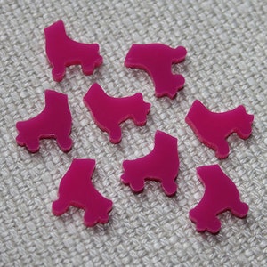 May include: Ten pink plastic roller skate charms. The charms are shaped like roller skates with wheels and are approximately 2.5 cm in size.