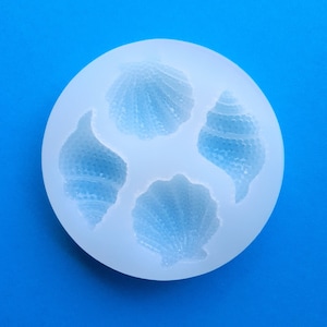 Puede incluir: Un molde de silicona transparente con cuatro formas de conchas diferentes. El molde está diseñado para hacer decoraciones comestibles para pasteles u otros postres.