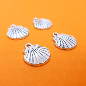May include: Four silver-colored seashell charms with a detailed design. The charms are on a bright orange background.