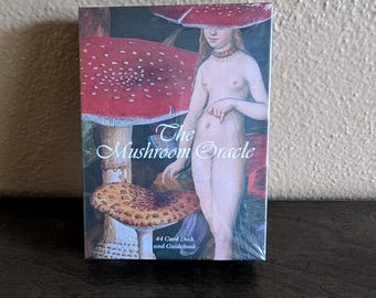 May include: A rectangular box set titled The Mushroom Oracle containing a 44 card deck and guidebook. The box features an illustration of a figure standing among large red and brown mushrooms, with the title text printed in white script.