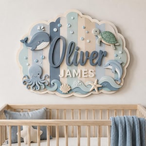 May include: A decorative wall sign featuring the names Oliver and JAMES in blue and white lettering. The sign has a scalloped edge and displays sea creatures including a whale, octopus, sea turtle, dolphin, starfish, and seashell on a striped background.