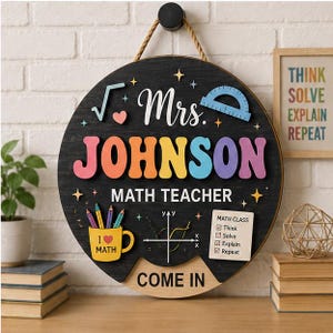 Puede incluir: Un letrero redondo de madera negra con cuerda para colgar que muestra el texto Mrs. JOHNSON MATH TEACHER y COME IN. Incluye gráficos coloridos en relieve de un símbolo de raíz cuadrada, un transportador, una taza amarilla y una lista.