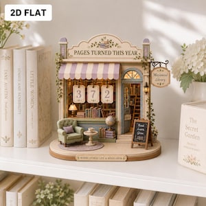Könnte beinhalten: Ein Miniatur-Bibliotheksmodell mit der Aufschrift Pages Turned This Year, einem gestreiften Vordach, einem grünen Sessel, einem Globus und einem Schild mit der Aufschrift Maplewood Library. Innen sind Bücherregale, ein Tisch und ein Read Learn Grow Schild.