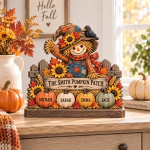 May include: A decorative tabletop sign featuring a scarecrow wearing a hat with a black bird, sunflowers, and autumn leaves. A wooden fence backdrop displays the text THE SMITH PUMPKIN PATCH above four pumpkins personalised with the names MICHAEL, SARAH, EMMA, and JACK.