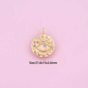 May include: Gold-toned pendant charm with a white opal eye design, surrounded by clear rhinestones and a pink rectangular stone. Size: 21.6x15x2.6mm.