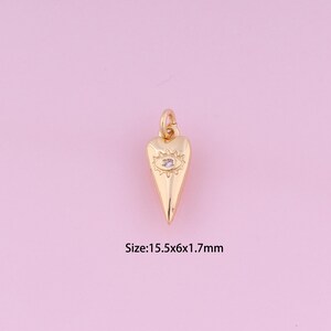 Puede incluir: Encanto de corazón dorado con un pequeño ojo de cristal transparente en el centro. El encanto tiene 15,5 mm de ancho, 6 mm de alto y 1,7 mm de grosor.