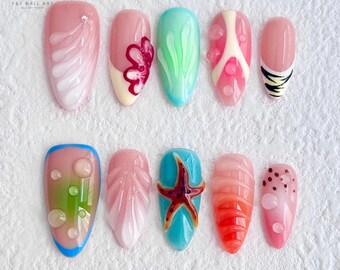May include: Ten different nail designs featuring a summer beach theme. The designs include seashells, starfish, coral, bubbles, and seaweed. The nails are painted in shades of pink, blue, green, and white.