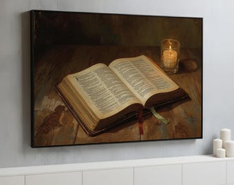 May include: A framed print of an open book with text, a red ribbon, and a lit candle in a glass. The artwork is a still life with warm tones, depicting a wooden surface and a dark background.