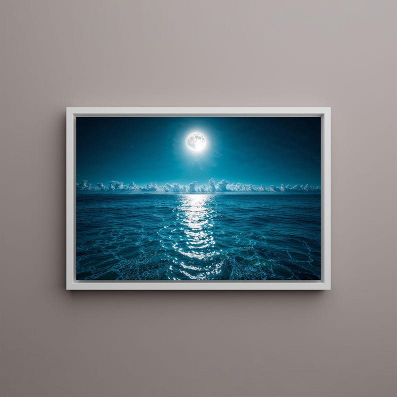 May include: A framed print of a moonlit ocean scene. The image features a full moon shining brightly above the water, with its reflection creating a shimmering path across the dark blue sea. White clouds are visible on the horizon.