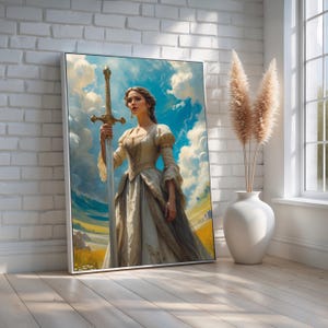 May include: Framed artwork depicting a woman in a flowing gown holding a sword against a backdrop of a cloudy sky and a golden field. The artwork is in a white frame and leans against a white brick wall.