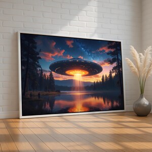 May include: A framed art print depicts a UFO hovering over a lake at sunset. The spacecraft emits a bright light beam. The scene includes a forest, water, and a colorful sky with clouds. Two figures stand on the shore.