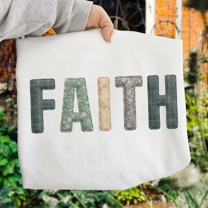 May include: White tote bag with the word "FAITH" appliqued in various patterned fabrics. The letters are in shades of green, beige, and blue, with a plaid and floral design. The bag is held by a person.