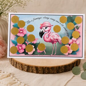May include: A decorative card featuring a pink flamingo wearing a hat, surrounded by pink flowers and gold scratch-off circles. The card has the text "Be a flamingo: classy, sassy and a bit smart-assy."
