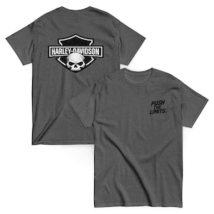 May include: Two charcoal gray t-shirts. One features a Harley-Davidson logo with a skull graphic on the back. The other shirt has "PUSH THE LIMITS" printed on the front. Both shirts have short sleeves and a crew neck.