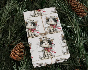 May include: A wrapped gift with a repeating pattern of a cartoon cat angel with a halo, wings, and a red bow. The gift is tied with twine and rests on a bed of green pine needles and pine cones.