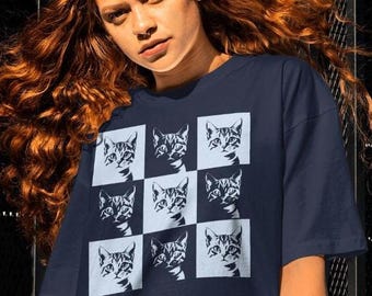 May include: A navy blue t-shirt featuring a repeating pattern of nine white outlined images of cats looking directly at the viewer.