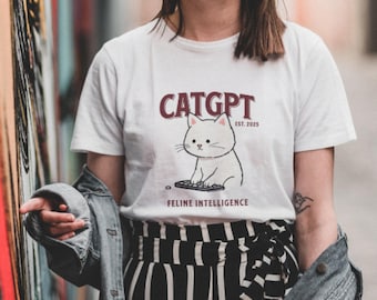 May include: White t-shirt with a graphic of a cat typing on a keyboard. The text on the shirt reads "CATGPT EST. 2023" and "FELINE INTELLIGENCE".