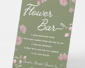 May include: A green card with the words "Flower Bar" in white script, with instructions for a flower arrangement. Pink floral accents and the text "Sarah's Bridal Shower August 3, 2026" are also present.