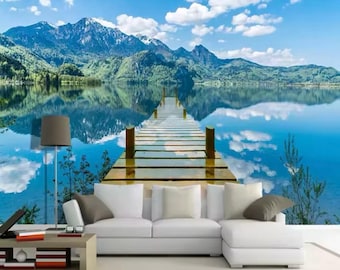 May include: A wooden jetty stretches out over a tranquil blue lake, mirroring the surrounding mountains and clouds in the water. The scene is idyllic and peaceful, perfect for a relaxing escape.