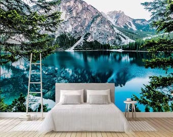 May include: A bedroom with a wall mural depicting a scenic view of a lake surrounded by snow-capped mountains and lush green trees. The lake reflects the sky and mountains, creating a serene and tranquil atmosphere.