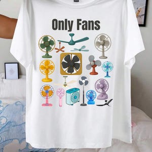 May include: White t-shirt with the text "Only Fans" in black. The shirt features a colorful illustration of various fans, including ceiling fans, desk fans, and handheld fans. The fans are in various colors and styles.