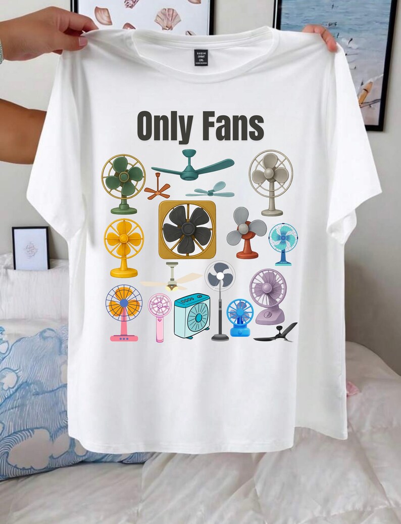 May include: White t-shirt with the text "Only Fans" in black. The shirt features a colorful illustration of various fans, including ceiling fans, desk fans, and handheld fans. The fans are in various colors and styles.