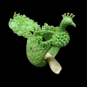 May include: A green peacock figurine with a detailed, textured design. The peacock has a crown, a long neck, and a fan-shaped tail. The figurine is made of a light green material and has a cream-colored base. The background is black.